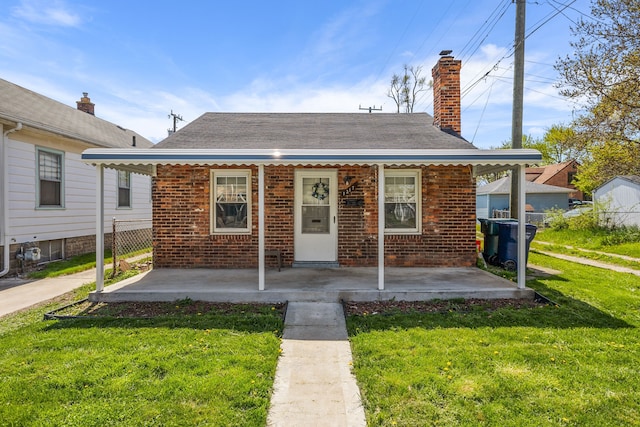 bungalow with brick siding, a porch, a chimney, and a front yard