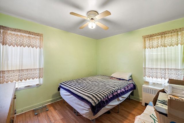 bedroom featuring ceiling fan, baseboards, wood finished floors, and radiator heating unit