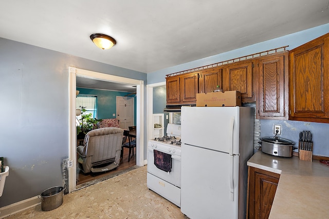 kitchen featuring brown cabinets, under cabinet range hood, white appliances, light countertops, and light floors