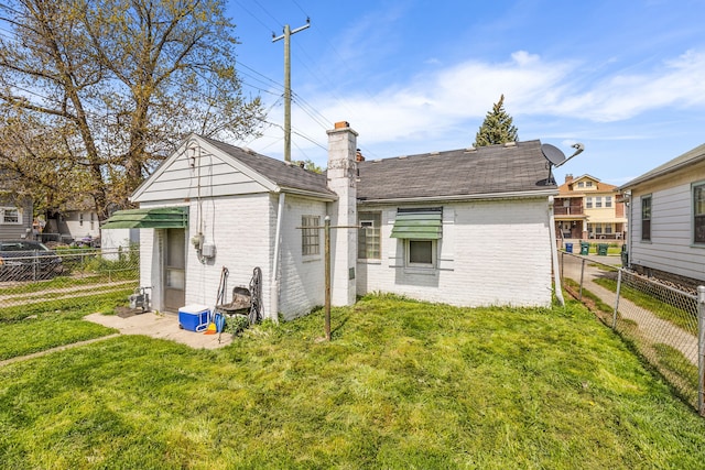 back of property featuring brick siding, a lawn, a chimney, and a fenced backyard