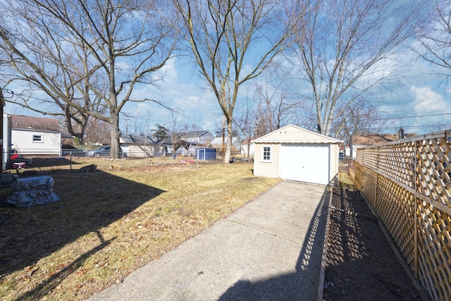 view of yard with a fenced backyard, a garage, concrete driveway, and an outdoor structure