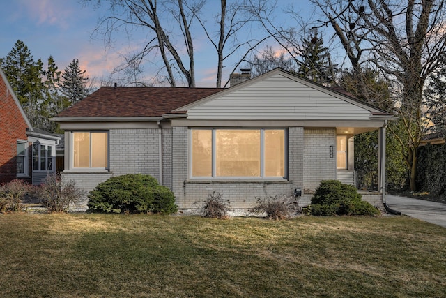 view of front of property with brick siding, a chimney, and a front yard