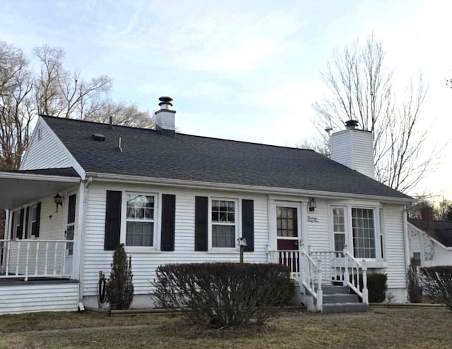 ranch-style home featuring a chimney and a shingled roof