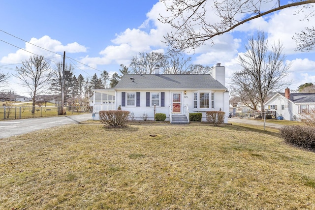 view of front of home featuring entry steps, a front lawn, fence, and a chimney