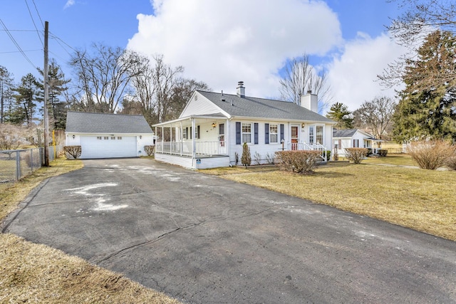 view of front of home with fence, covered porch, a chimney, an outdoor structure, and a front lawn