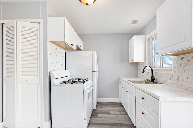 kitchen with visible vents, backsplash, white gas stove, light countertops, and a sink