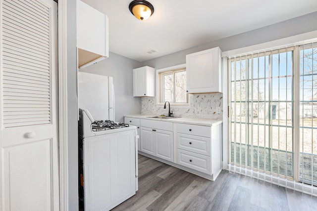 kitchen featuring white appliances, light wood finished floors, a sink, light countertops, and white cabinetry