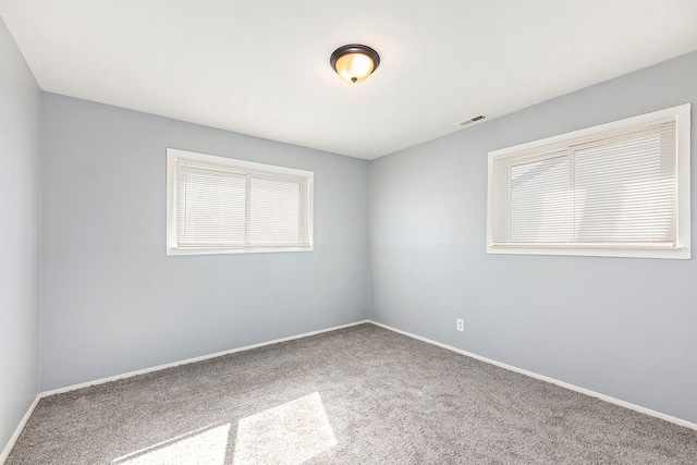 carpeted spare room with visible vents and baseboards