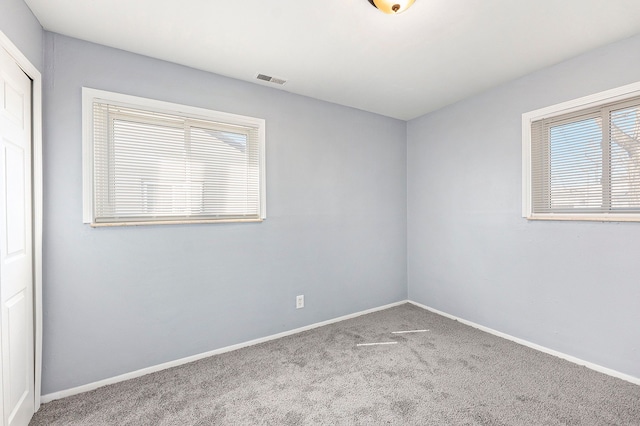 carpeted empty room with visible vents and baseboards