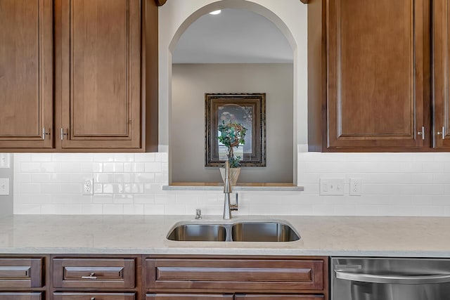 kitchen featuring a sink, tasteful backsplash, stainless steel dishwasher, and light stone counters