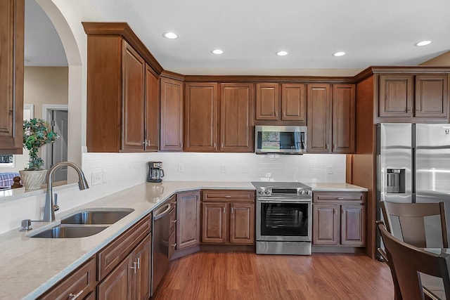 kitchen featuring wood finished floors, recessed lighting, a sink, stainless steel appliances, and tasteful backsplash