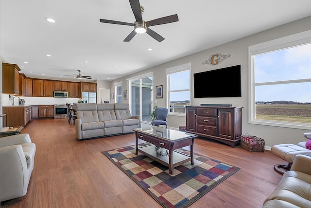 living area featuring recessed lighting, a ceiling fan, baseboards, and wood finished floors