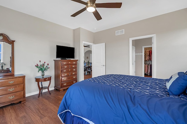 bedroom featuring a ceiling fan, wood finished floors, visible vents, baseboards, and arched walkways