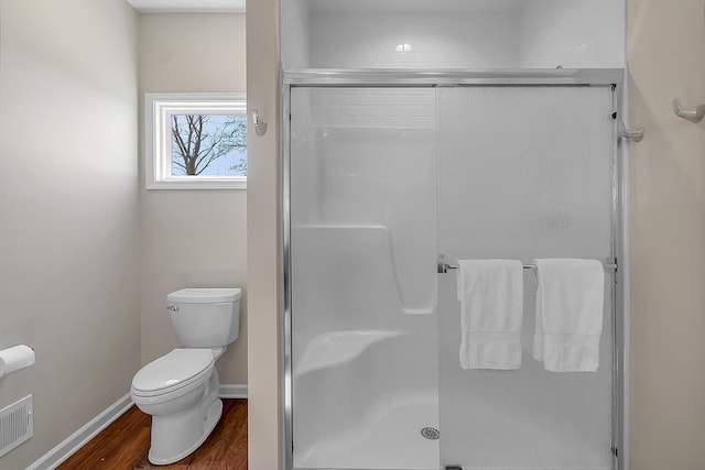 full bathroom with visible vents, toilet, wood finished floors, a shower stall, and baseboards