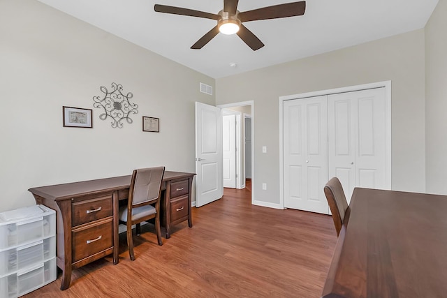 office space featuring a ceiling fan, wood finished floors, visible vents, and baseboards