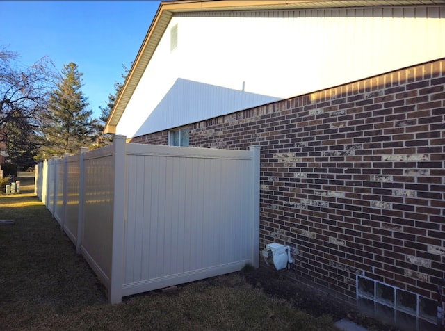 view of property exterior featuring brick siding and fence