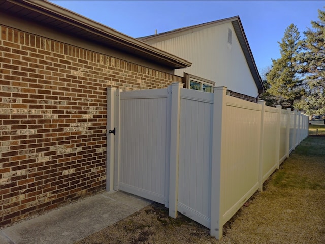 view of side of home featuring fence and brick siding