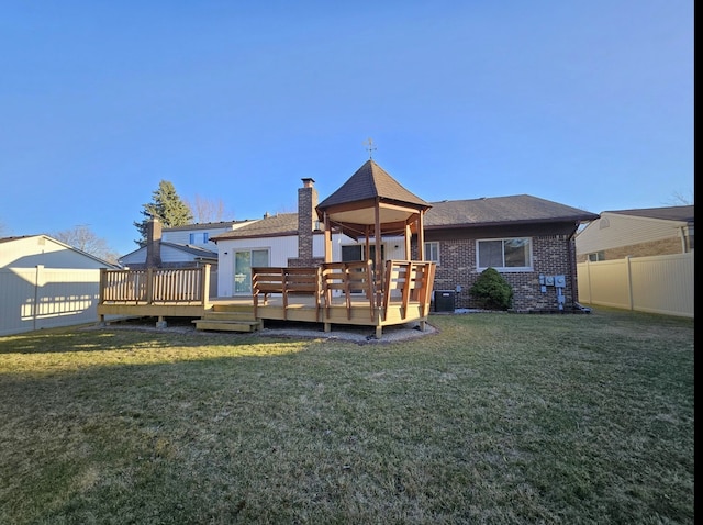 rear view of house featuring a yard, a fenced backyard, brick siding, and a wooden deck