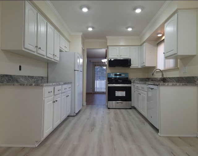 kitchen with light wood-type flooring, dark stone counters, white appliances, white cabinets, and crown molding