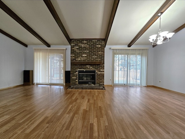 unfurnished living room with baseboards, a chandelier, lofted ceiling with beams, a fireplace, and wood finished floors