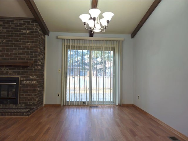 unfurnished living room with a chandelier, visible vents, a fireplace, and wood finished floors