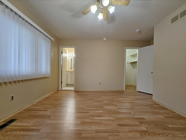 interior space featuring a ceiling fan, light wood-style floors, visible vents, and baseboards