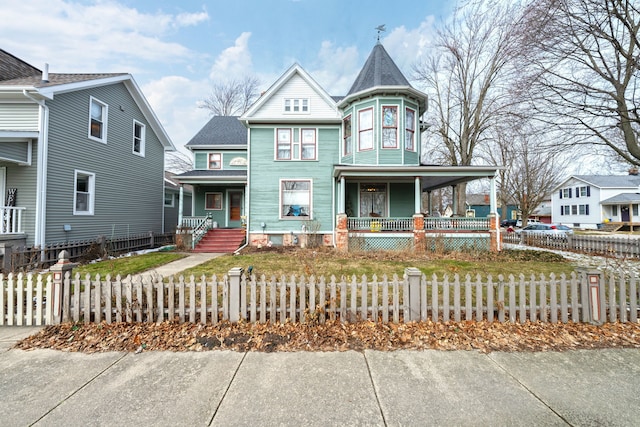 victorian house featuring covered porch and a fenced front yard