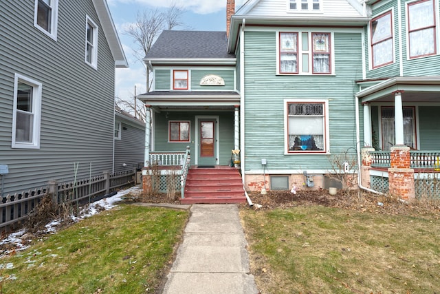 view of front of house featuring covered porch, a chimney, a front yard, and roof with shingles