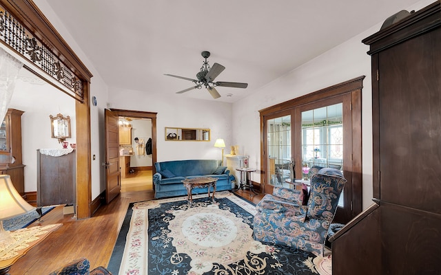 living room with a ceiling fan, wood finished floors, and baseboards