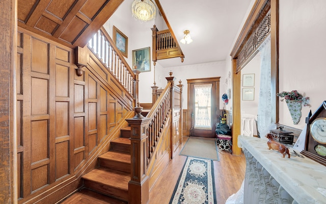 foyer featuring stairway, light wood-type flooring, and wainscoting