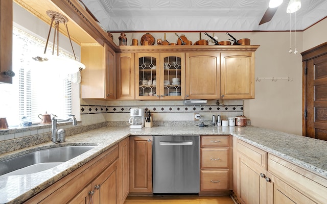 kitchen with light stone counters, a sink, glass insert cabinets, stainless steel dishwasher, and tasteful backsplash