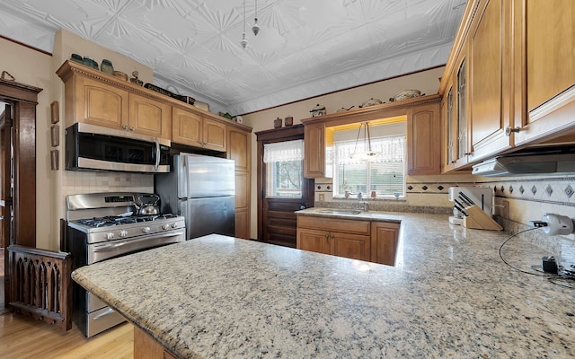 kitchen featuring a sink, an ornate ceiling, appliances with stainless steel finishes, a peninsula, and decorative backsplash