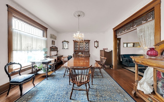 dining area with wood finished floors, a chandelier, and ornamental molding