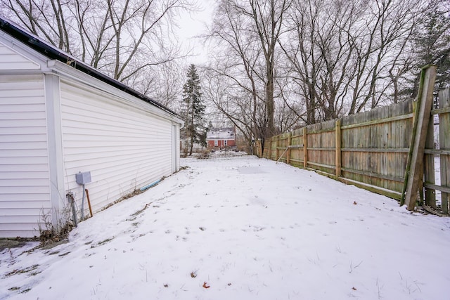 snowy yard with fence and a garage