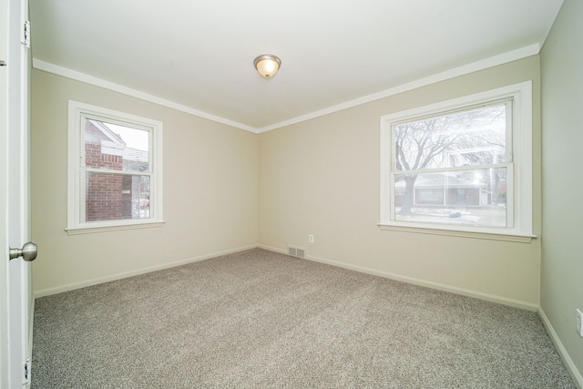 empty room featuring visible vents, carpet flooring, baseboards, and ornamental molding