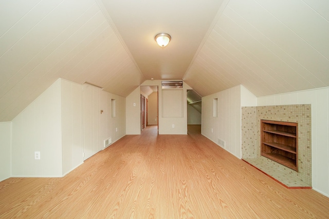 additional living space with vaulted ceiling, visible vents, built in features, and wood finished floors