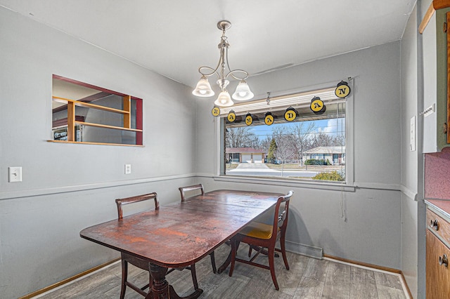 dining room featuring wood finished floors, baseboards, and a chandelier