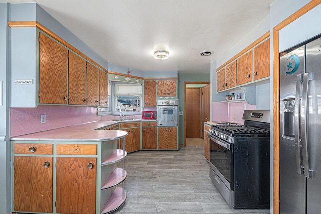 kitchen featuring visible vents, appliances with stainless steel finishes, light wood-style floors, brown cabinetry, and open shelves