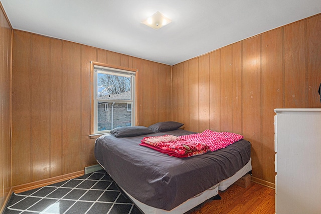 bedroom with wood walls, baseboards, and dark wood-style flooring