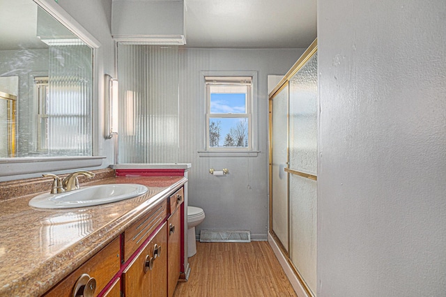 bathroom with visible vents, toilet, a stall shower, wood finished floors, and vanity