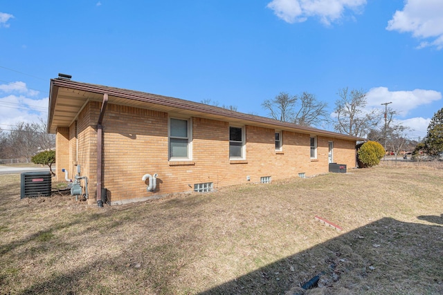 view of side of home with cooling unit, brick siding, and a lawn