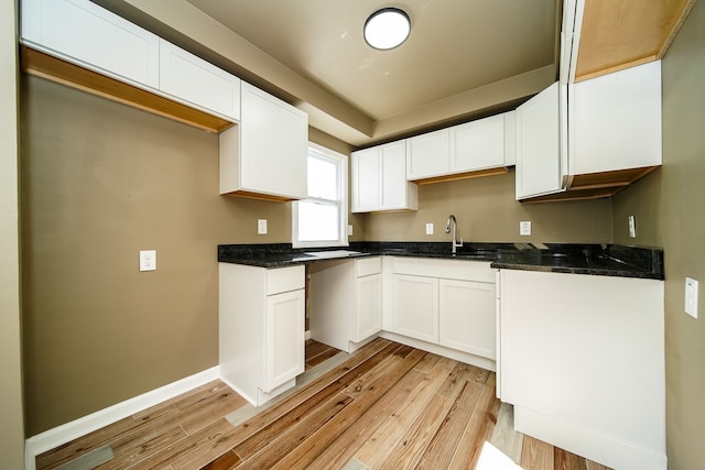 kitchen with white cabinets, light wood-style floors, and a sink