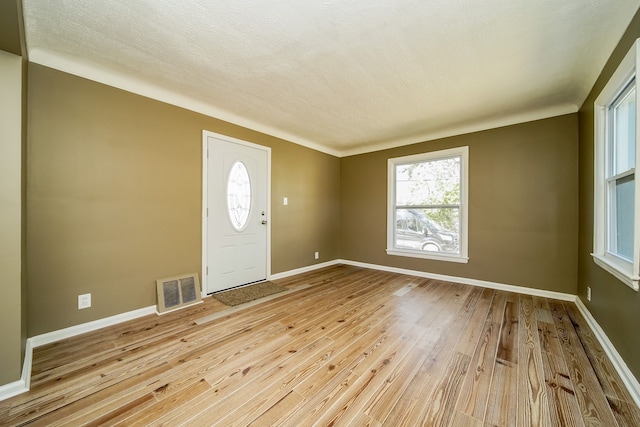 foyer entrance with hardwood / wood-style floors, baseboards, visible vents, and a textured ceiling