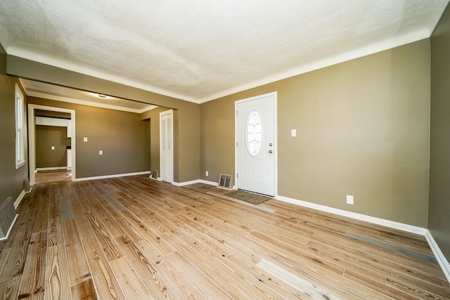 interior space featuring visible vents, a textured ceiling, baseboards, and wood finished floors