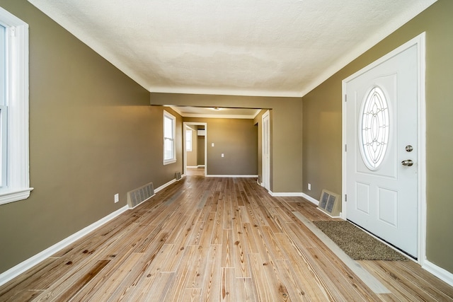 foyer featuring visible vents, light wood-style flooring, a textured ceiling, and baseboards