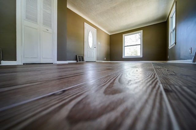 foyer entrance featuring wood finished floors, visible vents, baseboards, vaulted ceiling, and a textured ceiling