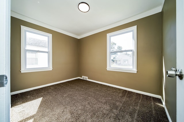 empty room featuring visible vents, dark carpet, plenty of natural light, and baseboards