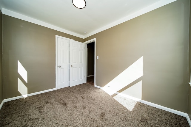 unfurnished bedroom with a closet, baseboards, and carpet floors