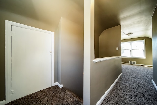 corridor featuring visible vents, baseboards, carpet, vaulted ceiling, and an upstairs landing