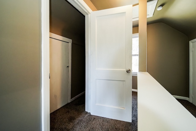 hallway featuring vaulted ceiling and dark carpet